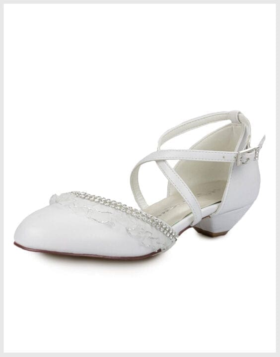 Foto zeigt weisse Kommunionschuhe mit einem kleinen Absatz, gekreuzten Riemchen und einem Glitzerelement mit Spitze