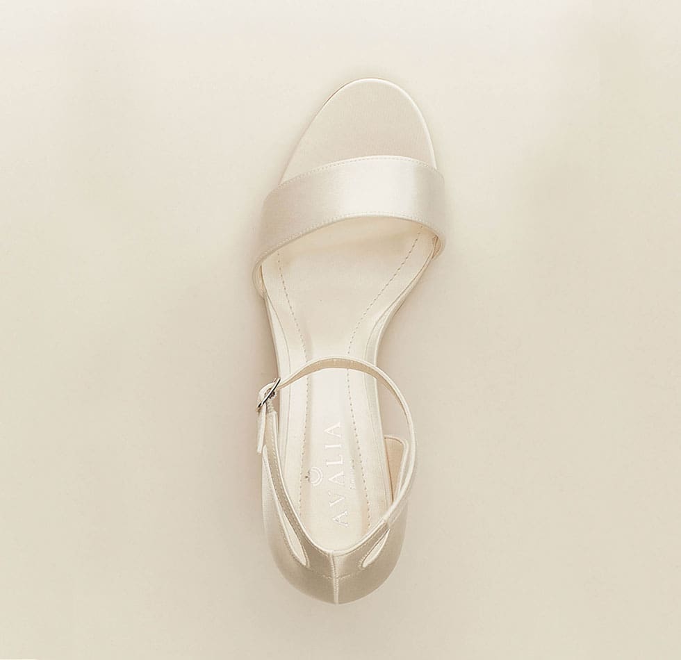 Auf dem Bild sind Brautschuhe zu sehen mit einem Riemen, vorne offen und einem kleinen Absatz in ivory
